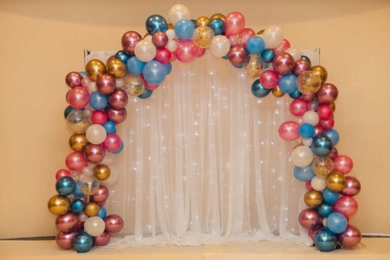 Elegant balloon backdrop with colorful organic balloon arch and white curtain photo booth decoration for birthdays, weddings, and celebrations.